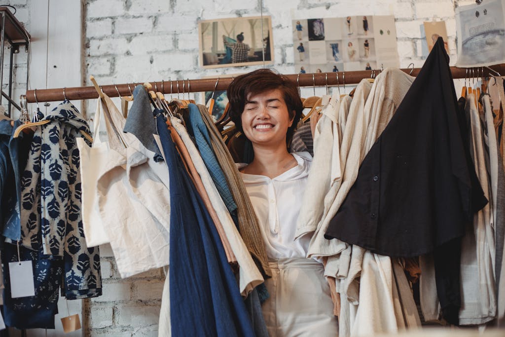 Smiling woman explores stylish clothing in a boutique, enjoying shopping indoors.